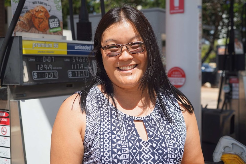 Amber Atterton stands in front of a fuel pump.