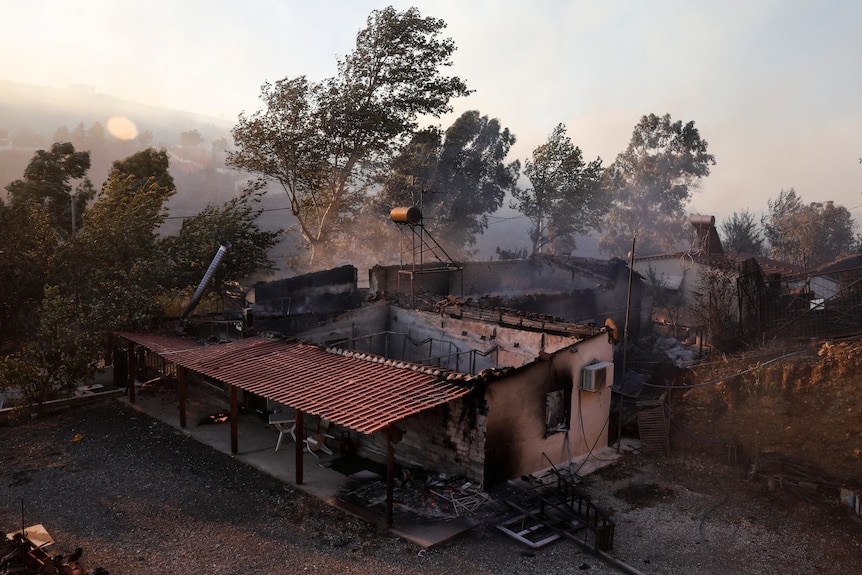 Casa in fiamme e tetto mancante.  Nebbia e fumo dell'albero sullo sfondo. 