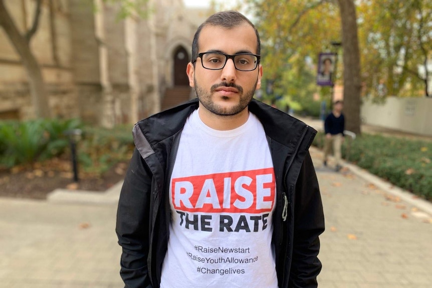 Ali Amin looks at the camera with a serious expression, while standing along an outdoor walkway at Adelaide University.