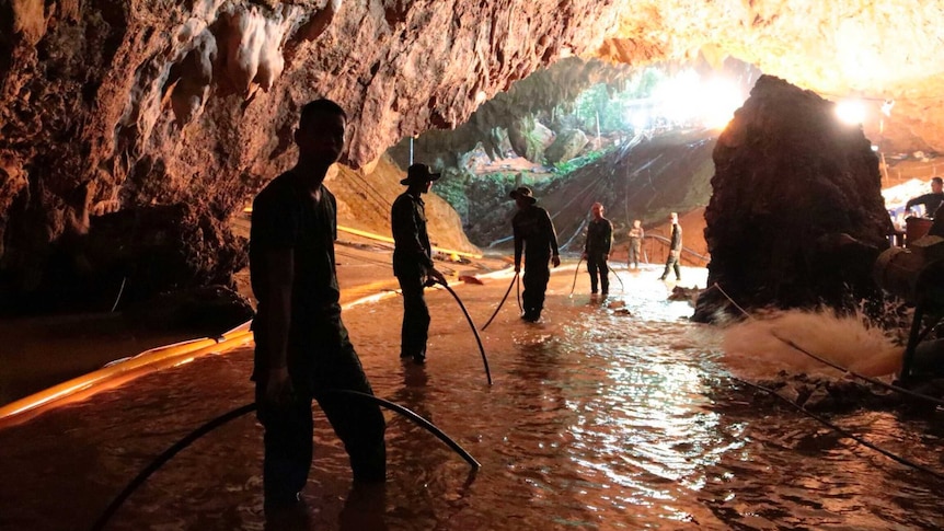 People stand in a dark and muddy cave.