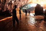 People stand in a dark and muddy cave.