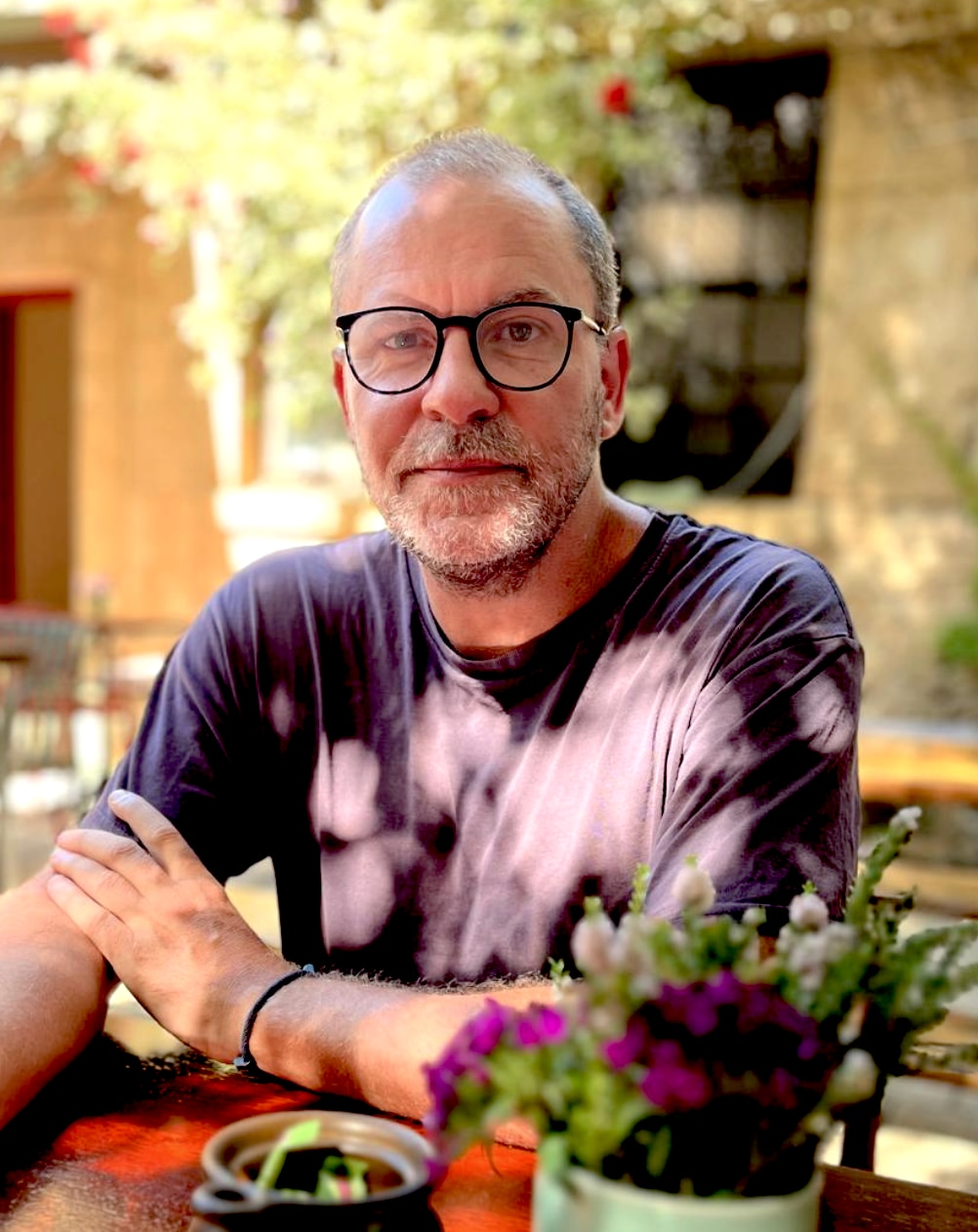 A man with glasses and a receding hairline looks at the camera