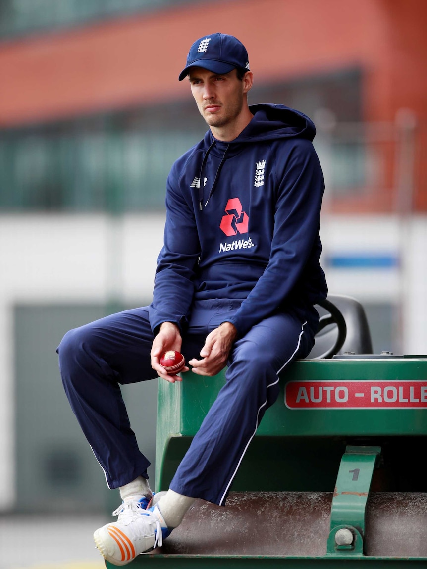 England cricketer Steven Finn wearing a training tracksuit and sitting on a turf rolling machine.