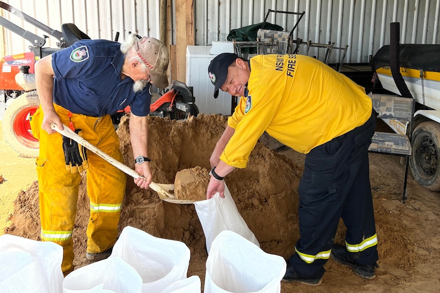 Two men with RFS uniforms on filling up sandbags.
