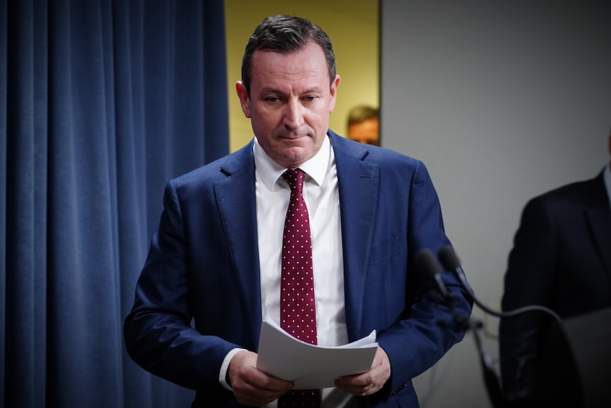 WA's Premier walks into a press conference holding papers