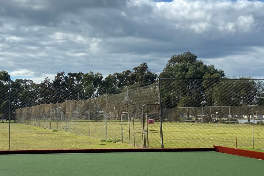 photo of old grass tennis courts with rundown fencing 