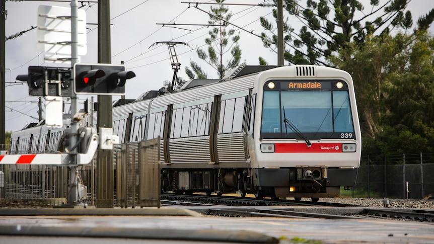 A Transperth train going through a level crossing from the front.