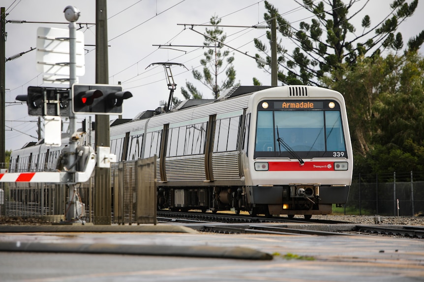 A Transperth train going through a level crossing from the front.