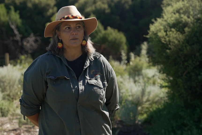 Photo of a woman standing in front of native bushes.