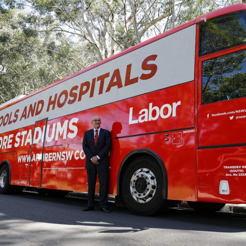 A man standing in front of a political campaign bus