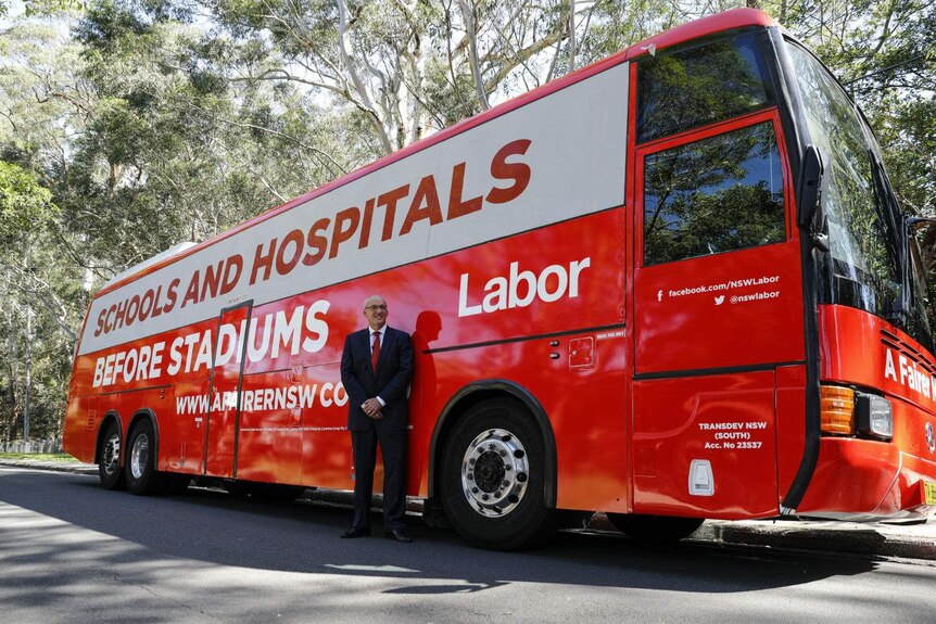A man standing in front of a political campaign bus