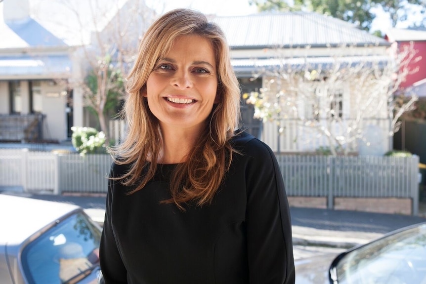 A woman on a street with a house in the background for a story on mistakes to avoid when trying to buy a house.