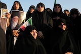 Women covered in black abiyas hold posters of the Supreme Leader Ayatollah Ali Khamenei.