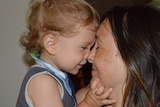 A little boy presses his nose up against his mother's.