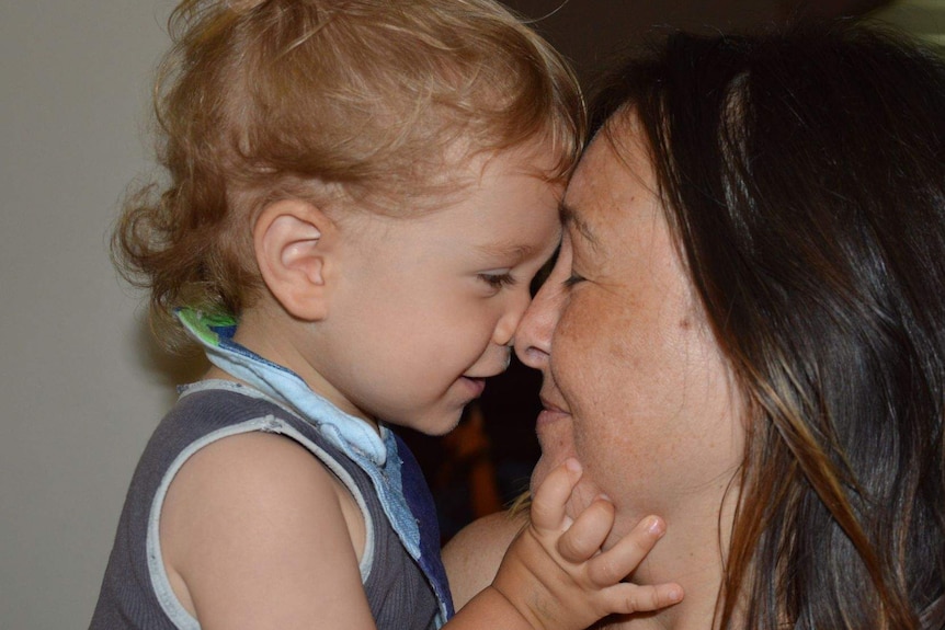 A little boy presses his nose up against his mother's.