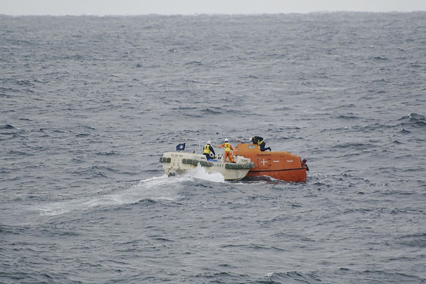 I membri della guardia costiera giapponese ispezionano una scialuppa di salvataggio della nave da carico Jin Tian che galleggia nel mare