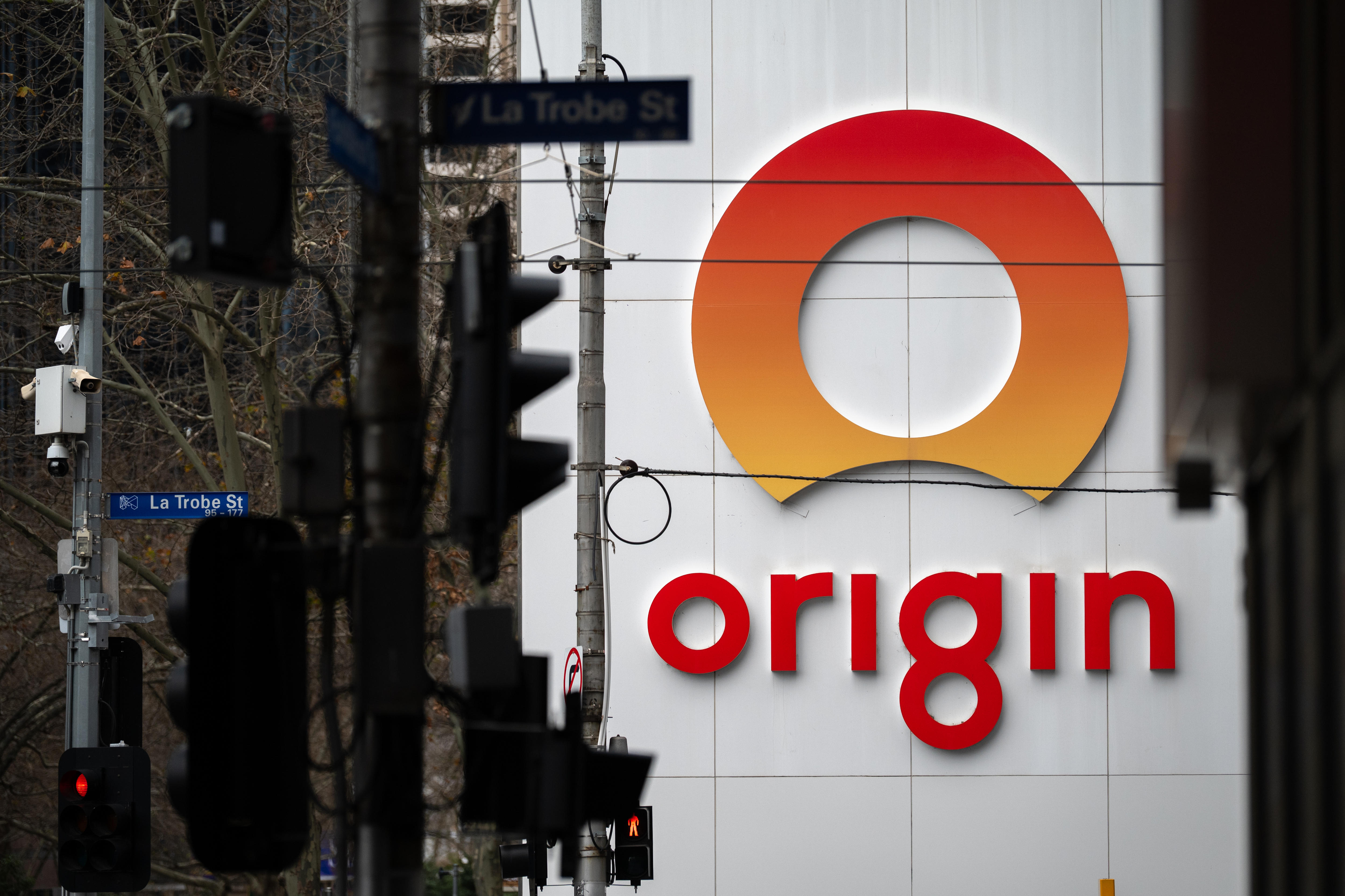 The orange Origin Energy logo on the outside of the business with traffic lights and street signs in the foreground.