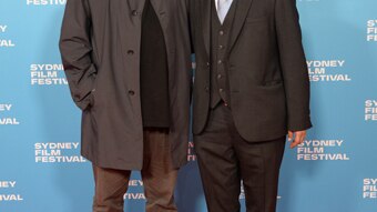 Two men in black standing on red carpet with blue Sydney Film Festival photo-wall behind.