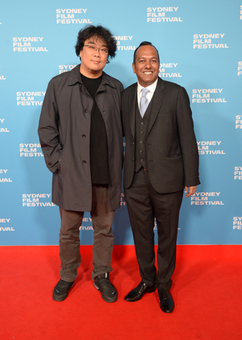 Two men in black standing on red carpet with blue Sydney Film Festival photo-wall behind.