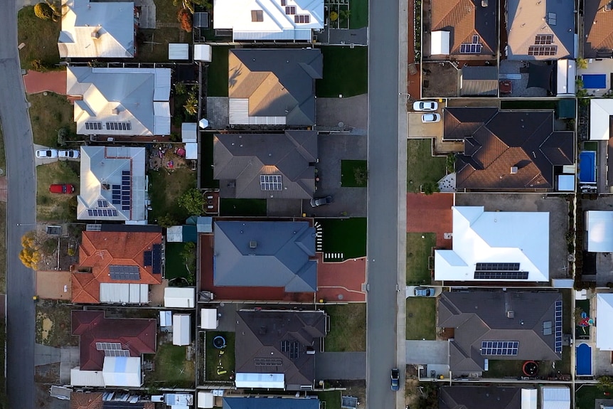 A birds-eye view of several houses. Some have pools in their backyard, some have solar panels.