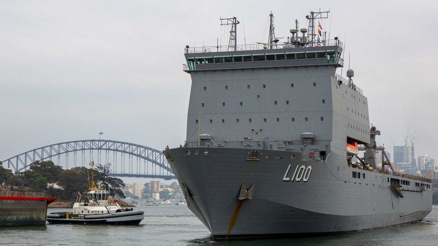 A naval vessel sails past the Sydney Harbour Bridge