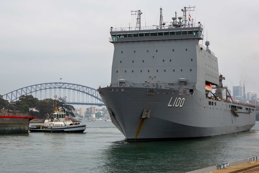 A naval vessel sails past the Sydney Harbour Bridge