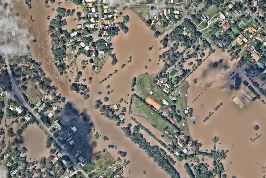 Aerial view of a farmhouse and outbuildings surrounded by brown muddy creek water.