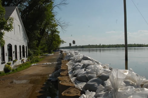 A temporary levee made of giant sandbags holds a swollen river at bay.