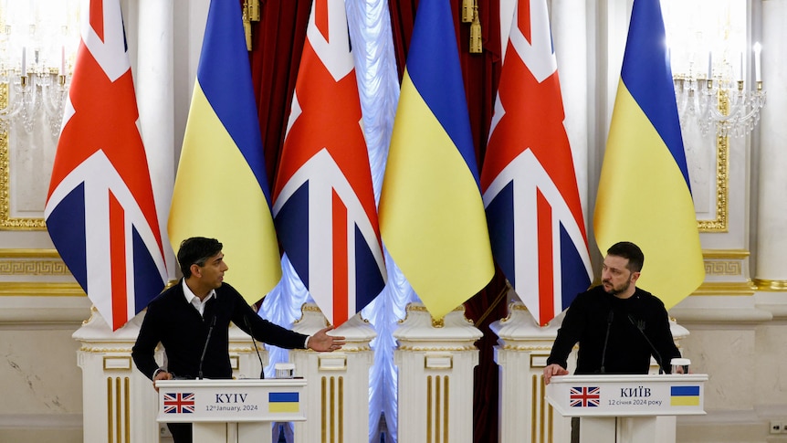 Rishi Sunak and Volodimir Zelenskyy stand together at podiums in front ok UK and Ukraine flags.
