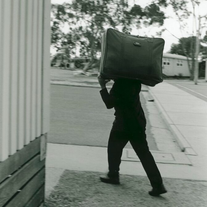 A man carries a suitcase on his shoulder at Puckapunyal Safe Haven, in 1999.