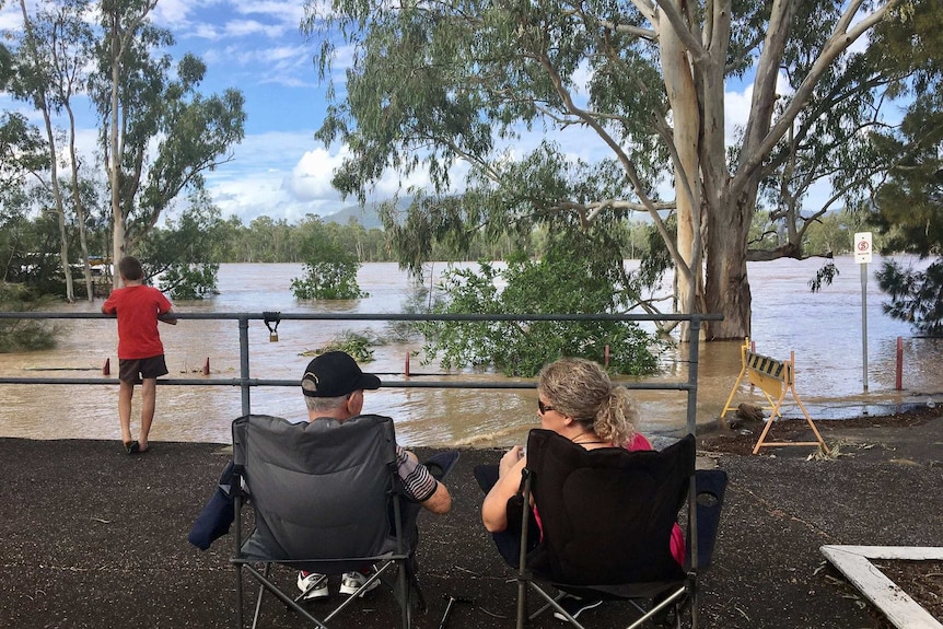 People set up camp chairs and watch the floodrivers rise