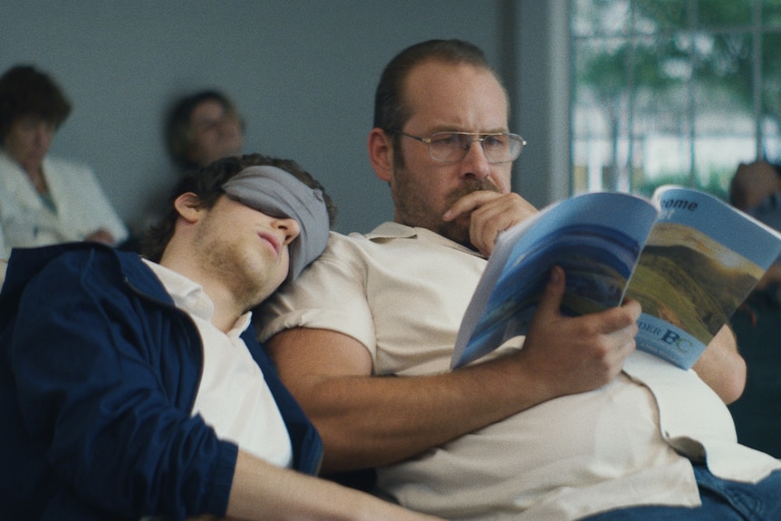 Babe Howard and Dean Imperial, a young man with eye mask resting on a middle aged man in aviator glasses, in the film Lapsis