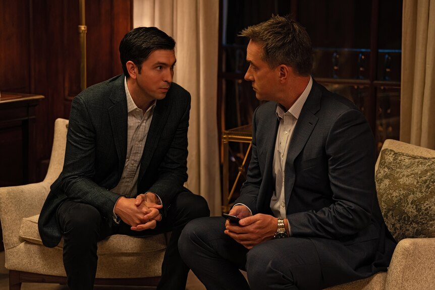 Still from TV show Succession: A man in his late 40s and a tall man in his early 30s, both in suits, sitting and talking