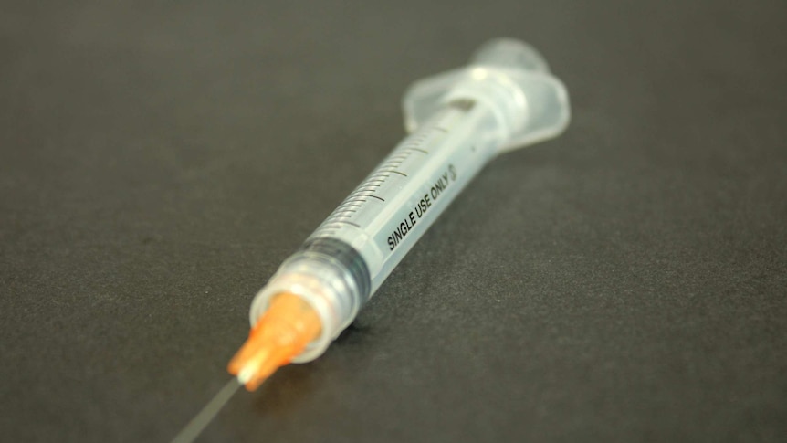 A syringe sitting on a table.