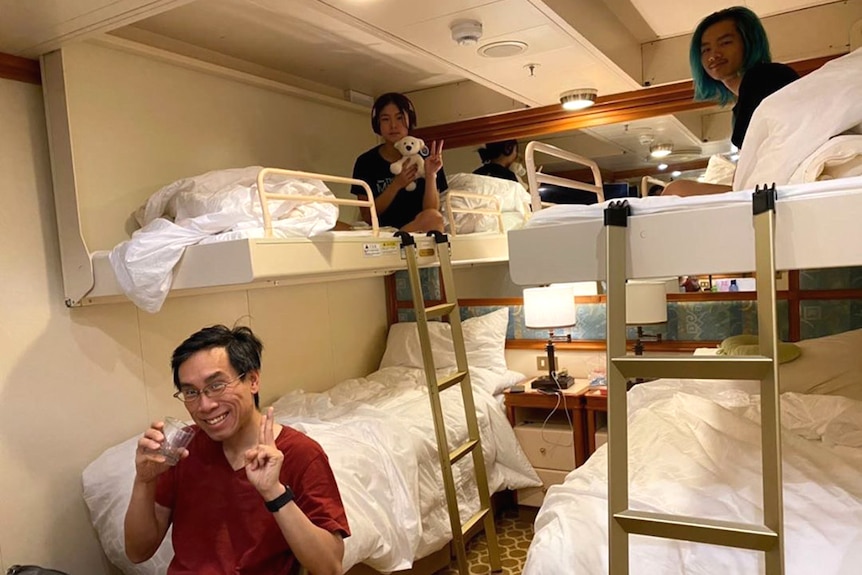 Three people sitting on bunk beds inside a ship's cabin