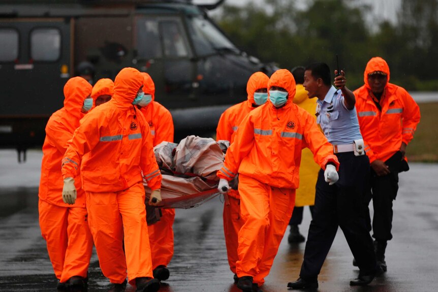 Search and rescue crews carry part of AirAsia QZ8501