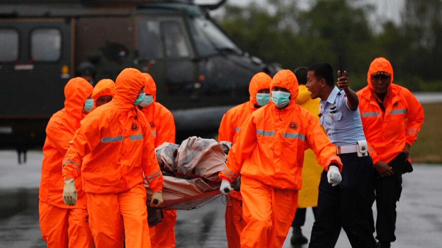 Search and rescue crews carry part of AirAsia QZ8501