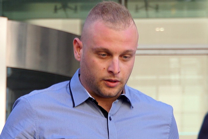 A man in a light blue shirt outside court.