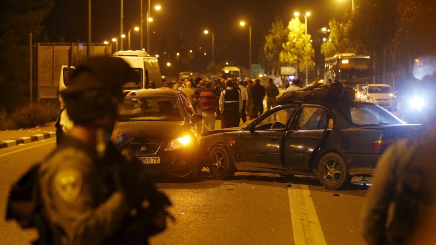 An Israeli policeman stands near the car of the Palestinian shooter.