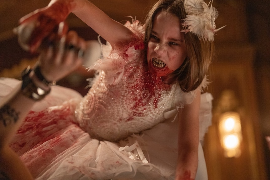 A young girl in a blood-soaked tutu snarls at the camera