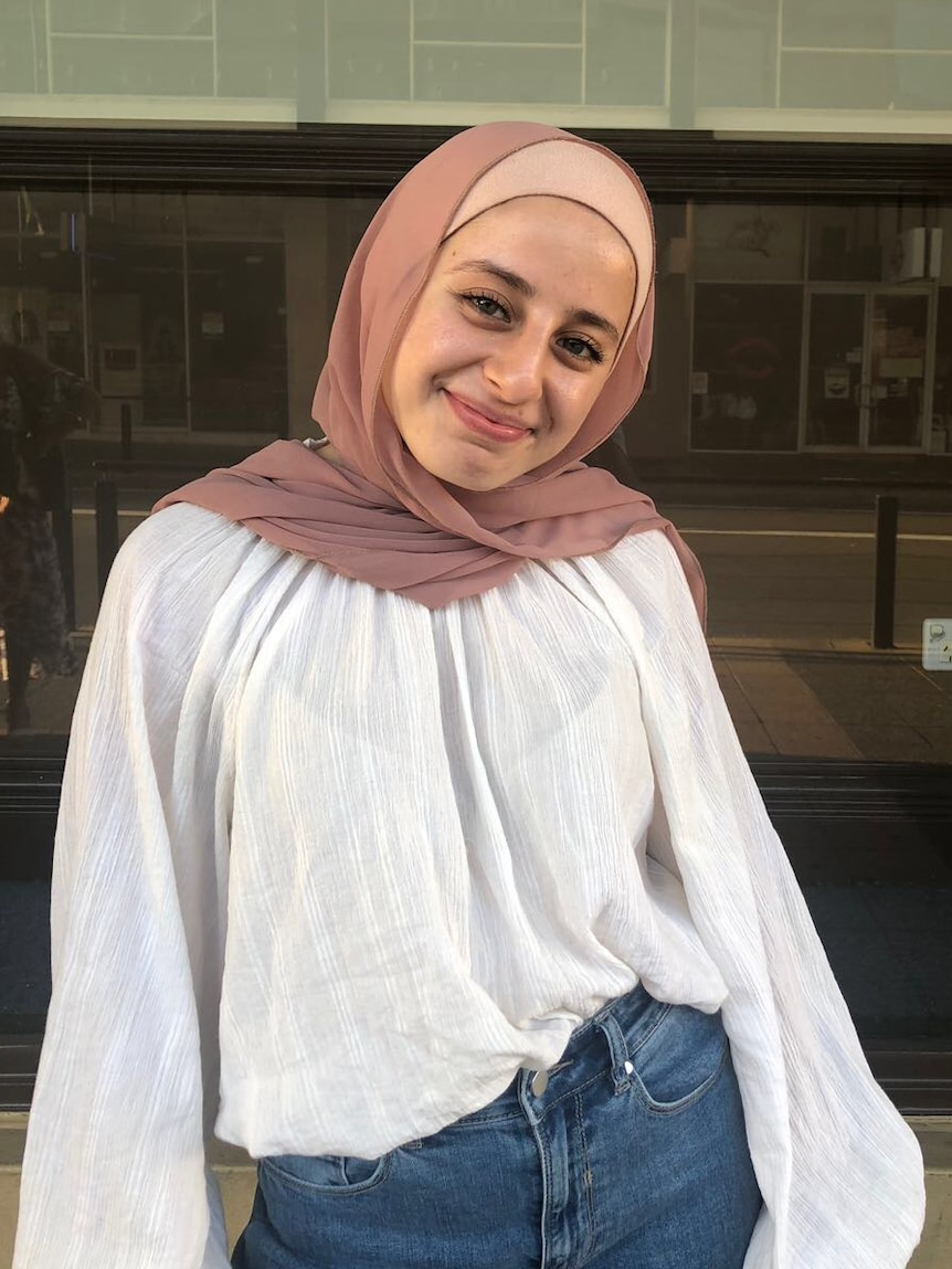 Portrait of Massilia Aili in a pink headscarf and dress smiling