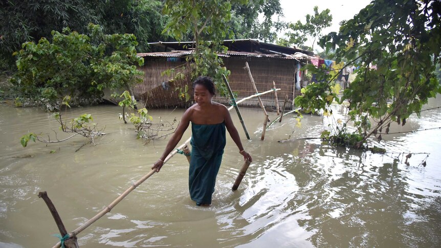 An Indian Bodo tribal woman crosses flood waters