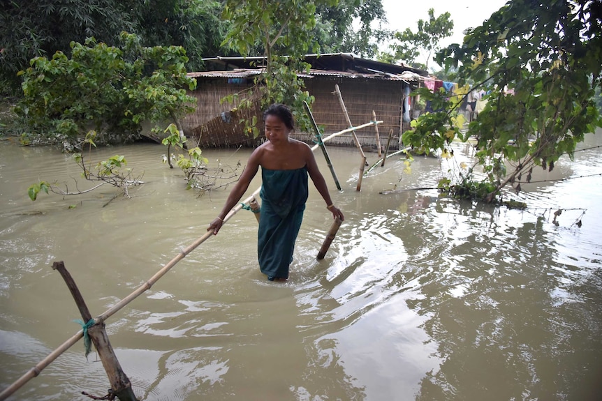 An Indian Bodo tribal woman crosses flood waters