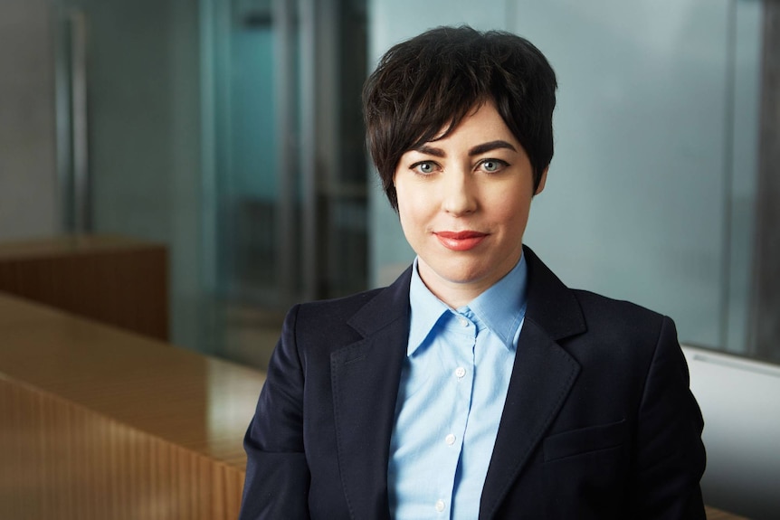 Woman with dark cropped hair wearing a shirt and blazer