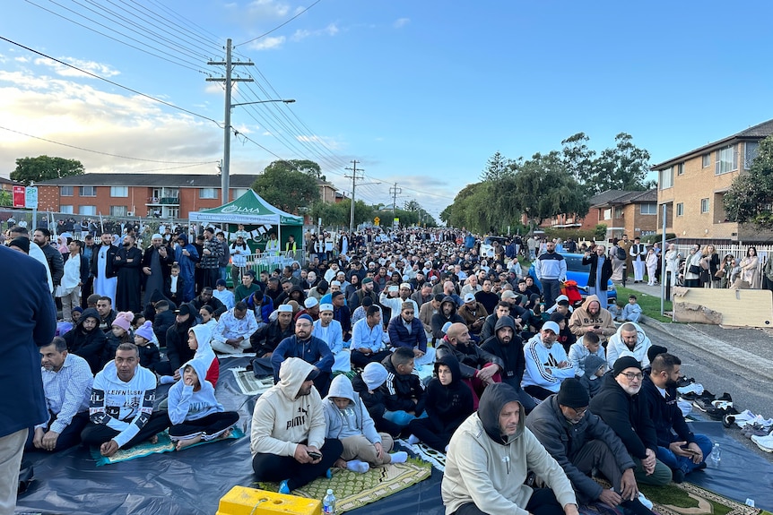 Hundreds of Muslims sit on the ground outside of Lakemba mosque waiting for prayer to commence.
