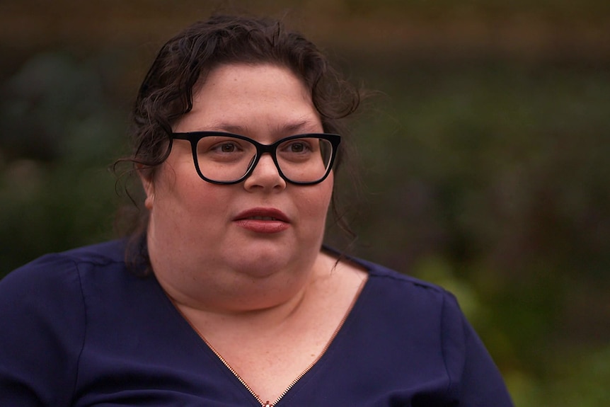 Woman with black-framed glasses wearing a blue shirt.