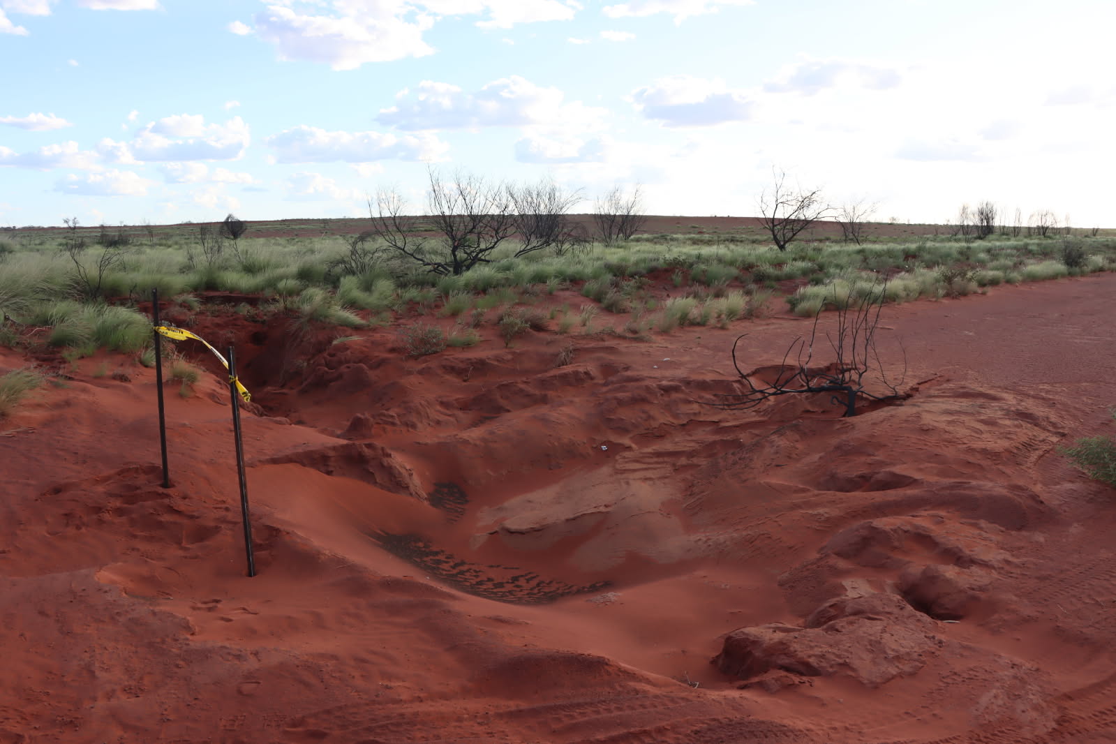 A large washout in a red dirt road.