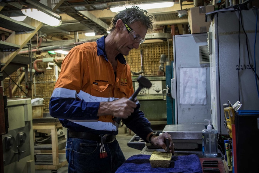 Mine worker with hammer about to stamp gold bar