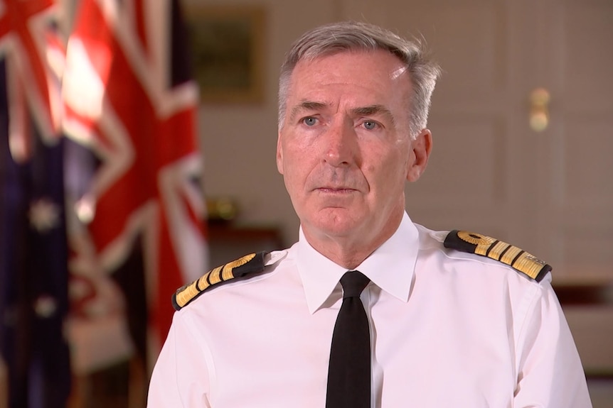 Tony Radakin in military dress sits in front of australian and united kingdom flags