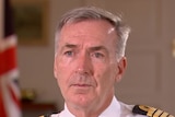 Tony Radakin in military dress sits in front of australian and united kingdom flags